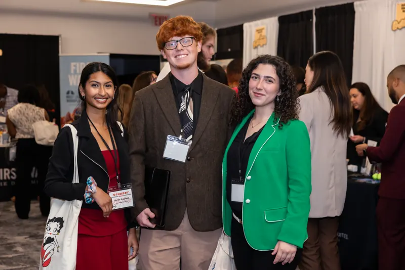 Three Rosen College students in business dress at an industry recruiting event