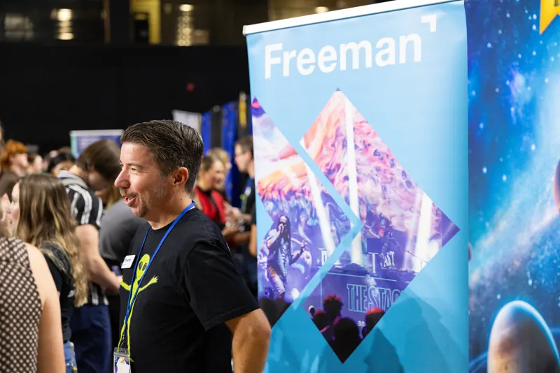 A Freeman representative meeting Rosen College students beside the company’s event display