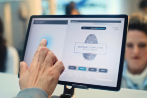 A hand touches a fingerprint scanning interface on a digital screen.