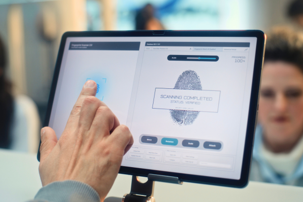 A hand touches a fingerprint scanning interface on a digital screen.