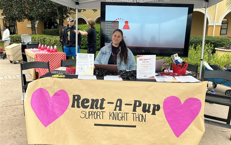 Junior lodging and restaurant management major McKenzie Brown, a member of POMP’s Rosen Miracle Makers, welcomes students at the Rent-a-Pup table while coordinating team registration and donations for Knight-Thon.